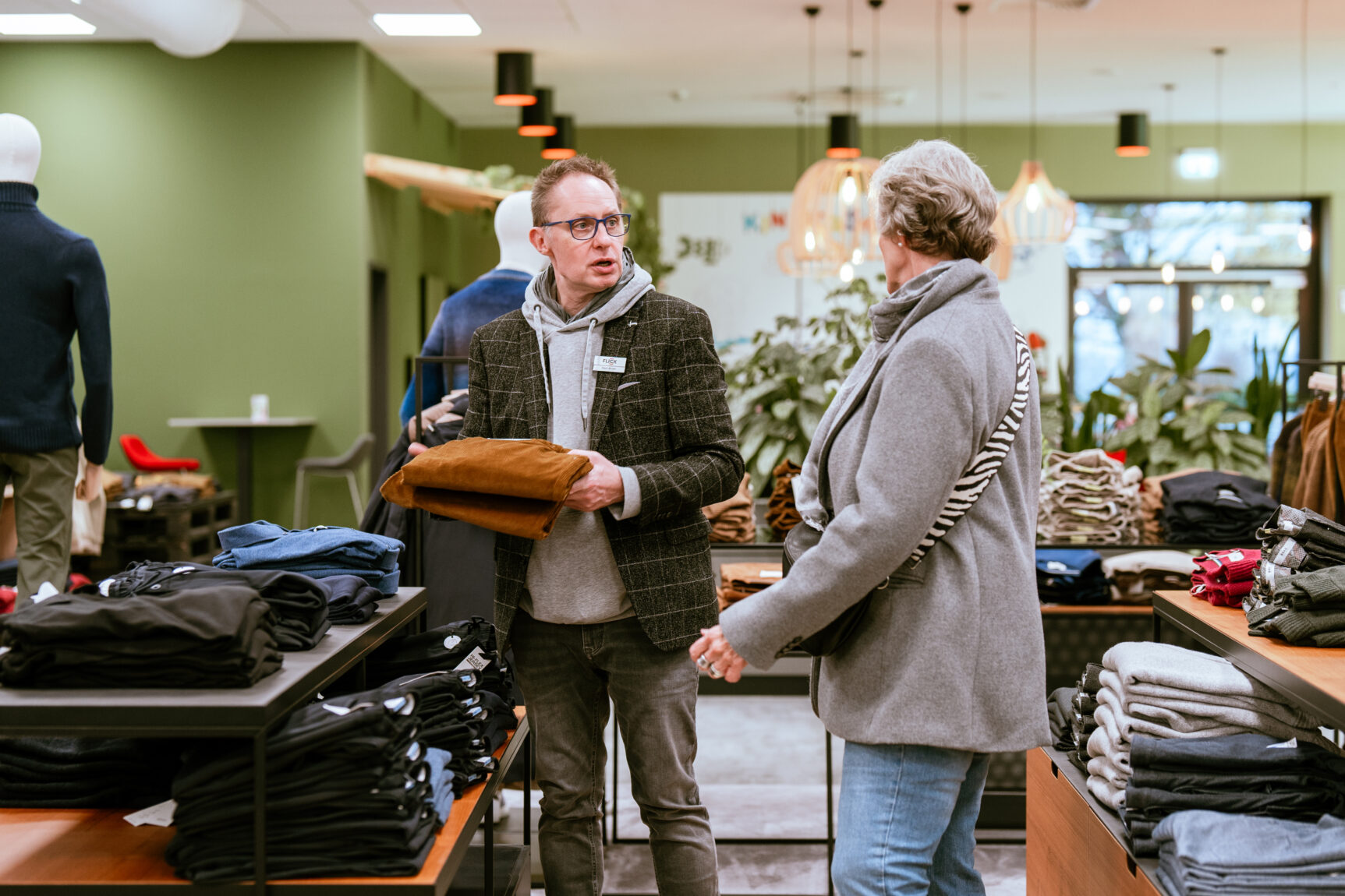 Mitarbeiter unterhält sich mit Kundin auf der Ladenfläche