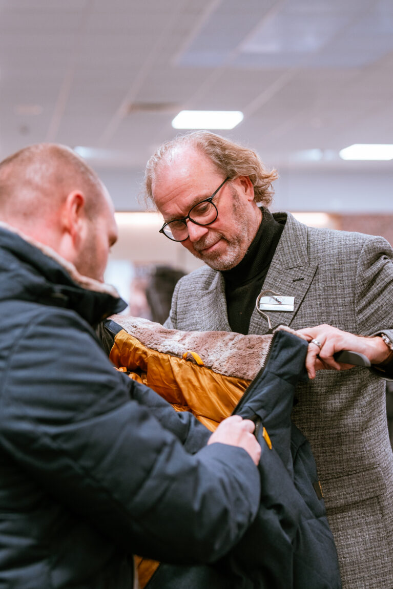 Mitarbeiter berät Kunden beim Kauf einer Jacke